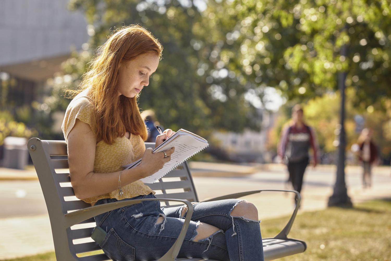 A <a href='http://kugywh.taxidalat24h.net'>全球十大赌钱排行app</a> student reads on a bench along Campus Drive.