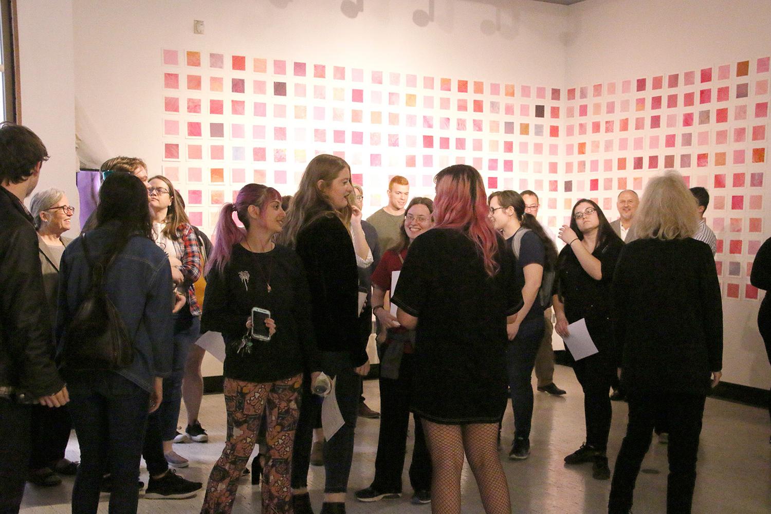 Students and visitors at a Spring 2019 Senior 的sis Opening. (in the background, paintings by Haley Schrock '19)